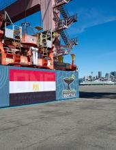 A shipping container with an Egypt flag banner at Terminal 46 with the Seattle skyline seen in the distance.